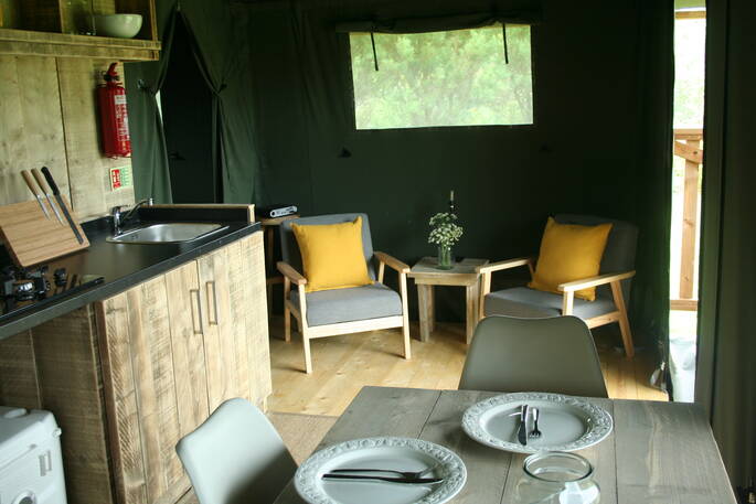 Inside of Mobbs living area with two chairs and kitchen area at Little Nook Glamping, Cornwall