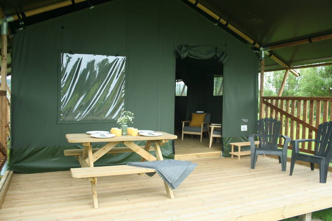 View of decking from outside of Mobbs with bench and seating area at Little Nook Glamping, Cornwall