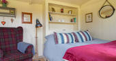 Close up of cosy double bed with grand arm chair beside it
