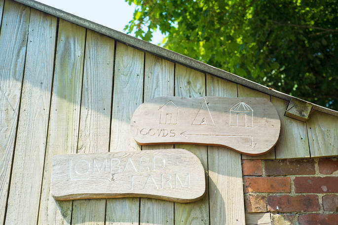 Two wooden signs with Lombard Farm engraved and directions to the Hut 