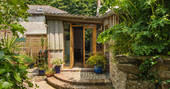 Front view of communal hub the Link with stone steps leading up to a glass door at Orchard Cabin, Cornwall
