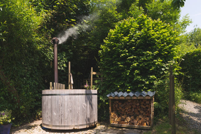 Communal wood-fired hot tub next to a shed with firewood