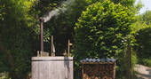 Communal wood-fired hot tub next to a shed with firewood