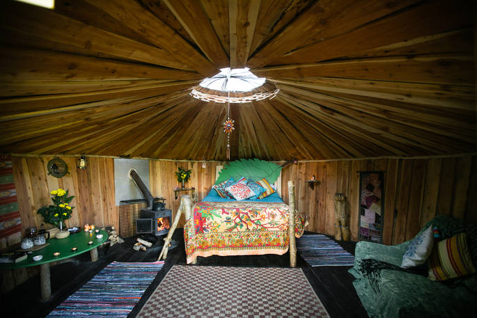 Interior of Pixie Yurt with double bed in the middle and circular roof light above at Mill Valley