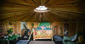 Interior of Pixie Yurt with double bed in the middle and circular roof light above at Mill Valley