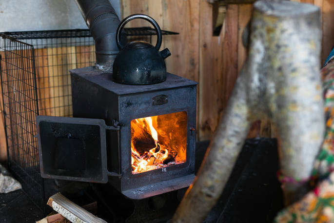 Roaring woodburner next to the bed inside of Pixie Yurt at Mill Valley