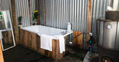 Communal bathroom with wood fired bath tub area for guests at Mill Valley in Cornwall 