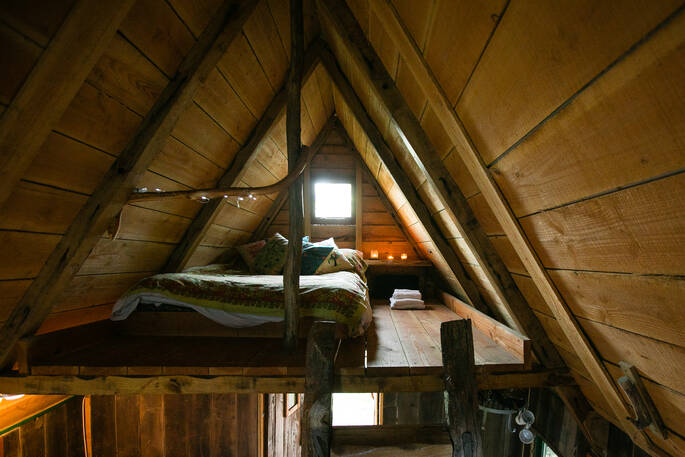 Double bed on mezzanine level inside of Woodland Cabin at Mill Valley in Cornwall 