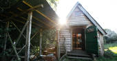 Front of Woodland Cabin with the sun shining through at Mill Valley in Cornwall