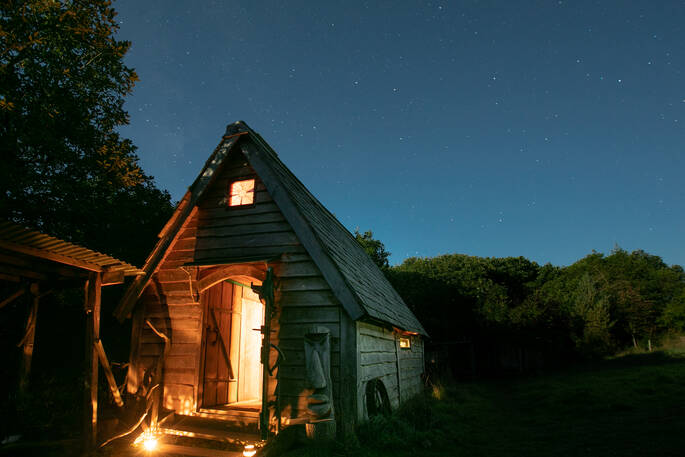 Woodland cabin glowing bright in the evening at Mill Valley in Cornwall