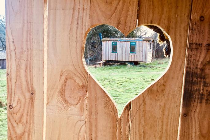 Woodland Hobbit house seen through a wooden heart at Mill Valley in Cornwall