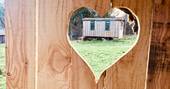 Woodland Hobbit house seen through a wooden heart at Mill Valley in Cornwall