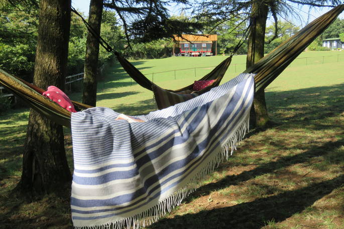 2 relaxing hammocks with blankets attached to the trees with the wagon in the background 