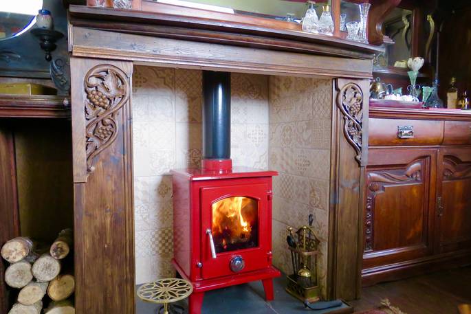 Lit enamelled cherry red wood-burner inside of Sangers Showmans Wagon in Cornwall 