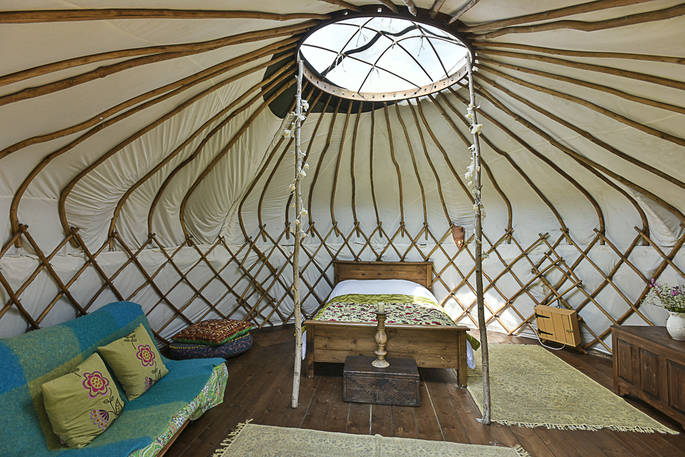 Cosy interior of Croglin Yurt with double bed and futon at Drybeck Farm in Cumbria