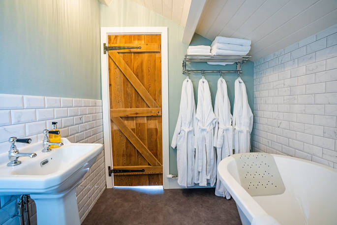 Cuckoo Cottage bathroom with bath tub and robes, Edenhall Estate, Penrith, Cumbria
