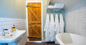 Cuckoo Cottage bathroom with bath tub and robes, Edenhall Estate, Penrith, Cumbria