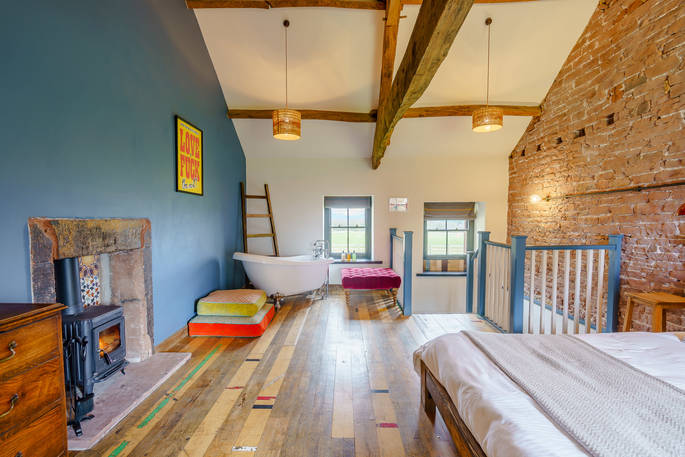 High Barn - bedroom with rolltop bath tub and wood burner, Edenhall Estate, Penrith, Cumbria