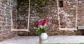 Two swings amongst traditional stone brick, at The Bothy at High Barn, in Cumbria