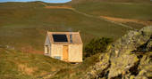 Hinterlandes Hidden Hut cabin exterior on a sunny day, Lake District, Lorton, Cumbria