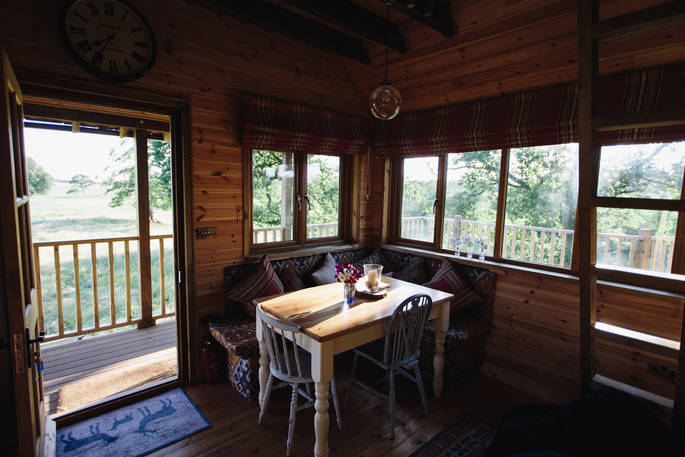 Inside the charming and rustic Netherby treehouse, with snug corner seating and dining table