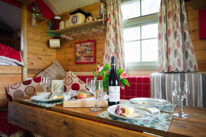 Delicious cheese and wine laid out on the table inside Fairfield shepherd's hut at Acorn Farm in Devon