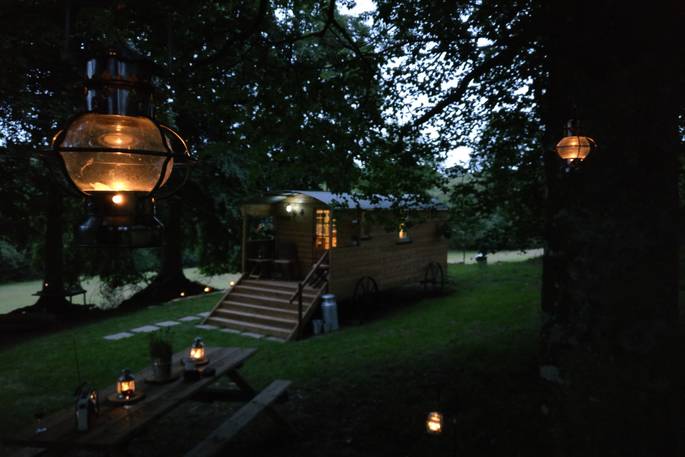Sit outside as the lanterns brighten the night sky outside of Fairfield shepherd's hut at Acorn Farm