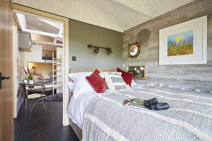 The cabin's bedroom and comfy double bed with nods to nautical with porthole window