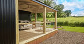 The covered deck and fire pit with views of the neighbouring barley fields at Brownscombe Luxury Glamping