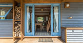 Doorway into Carpenter Cabin with store of firewood under covered veranda 