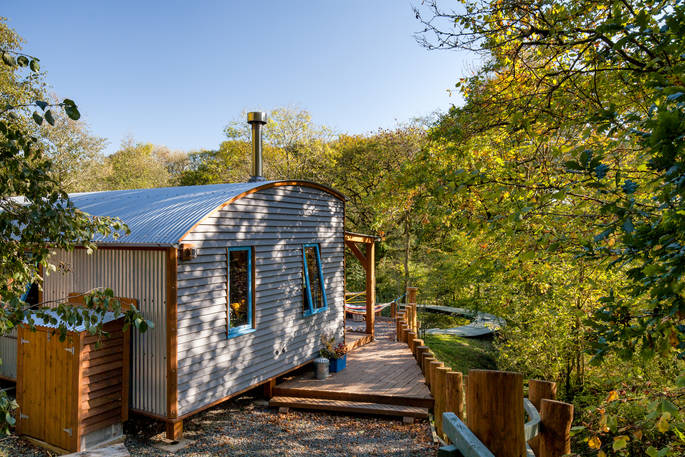 Carpenter Cabin shaded by trees on a sunny day at Devon Dens