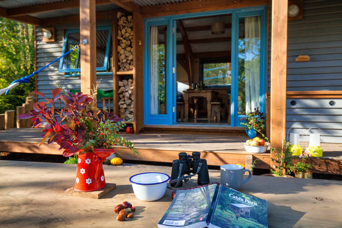 Vase, book and binoculars on the picnic table outside Carpenter Cabin at Devon Dens