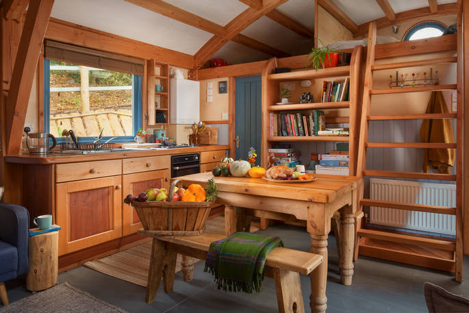 Dinner and a fruit and veg basket on the table inside Carpenter Cabin at Devon Dens