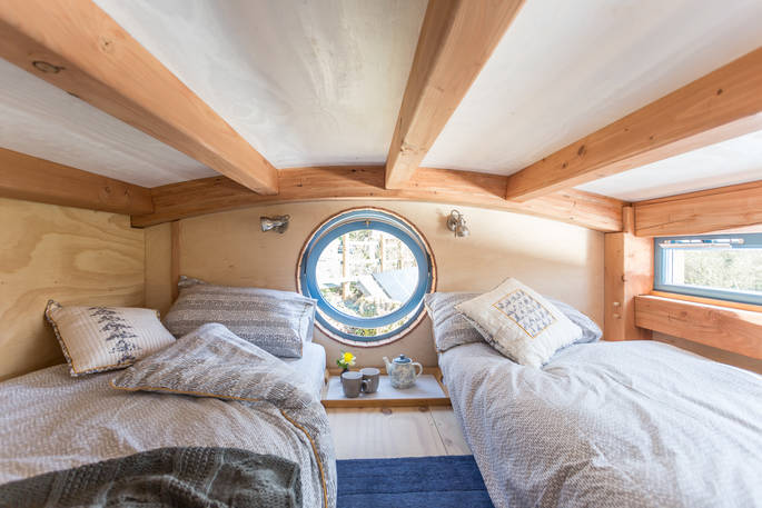 Twin beds on mezzanine level with circular window 