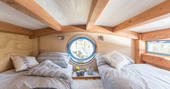 Twin beds on mezzanine level with circular window 