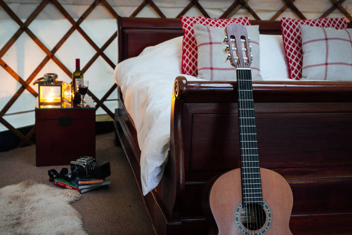 Guitar leaning against the double bed frame inside Great Links at Devon Yurt 
