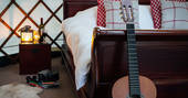Guitar leaning against the double bed frame inside Great Links at Devon Yurt 