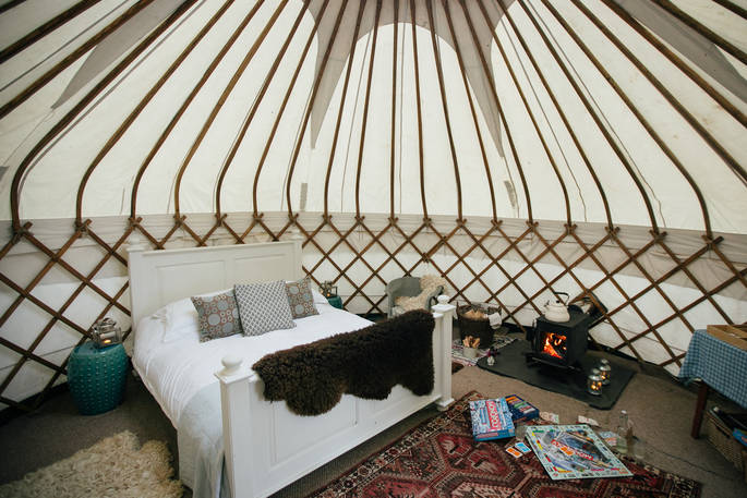 Interior of Little Links at Devon yurt with cosy double bed and lit wood-burner 