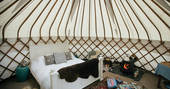 Interior of Little Links at Devon yurt with cosy double bed and lit wood-burner 