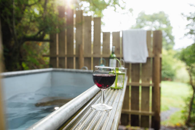 Glass of red wine on the edge of the outdoor wood-fired hot tub at Penn Farm 