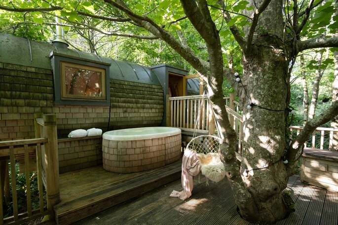 Outdoor hot tub and swing chair at Hideaway treehouse