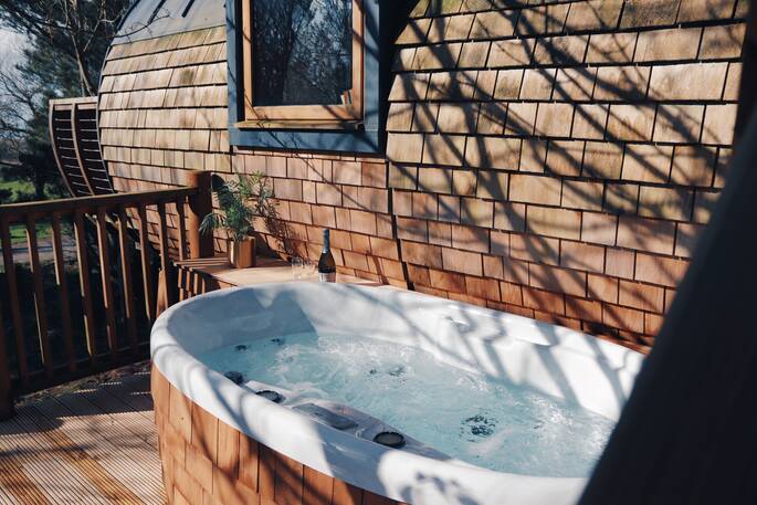 The hot tub on the deck at The Hideaway Treehouse at Pickwell Manor, Devon