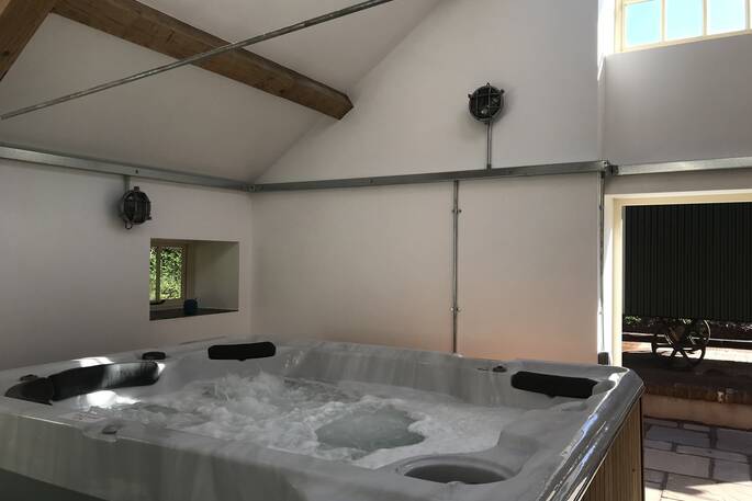 The amazing hot tub for guests at Scorlinch Shepherd's Hut, located inside the converted milking parlour