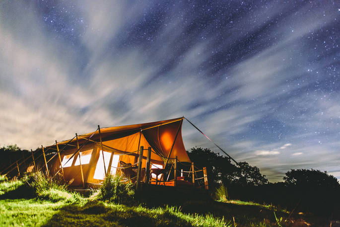 Exterior of Taw safari tent at Welcome Meadow in the night time at Devon
