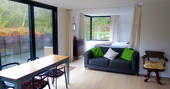 Open plan living space at Buck's Coppice cabin in Dorset with dining table, sofa and king-size bed