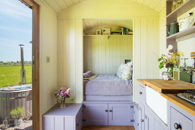 King size bed inside The Happy Hare with hot tub outside at Colber Farm in Dorset