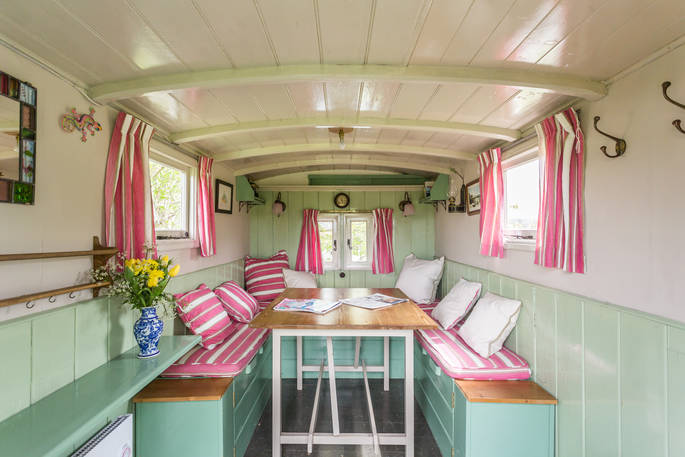 Mint green and stripy pink interior of the living van, made up as comfy dining area at Camping Coach, Dorset