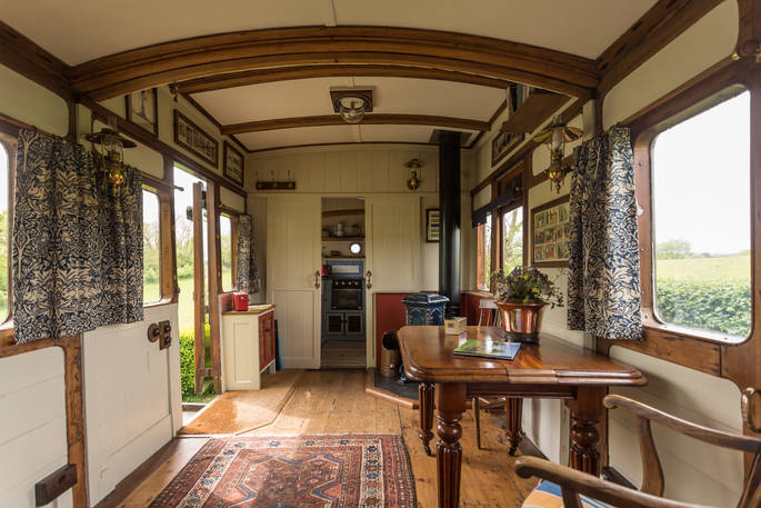 beautiful interior of vintage train carriage with mahogany panelling and a Persian rug on the floor at Camping Coach, Dorset