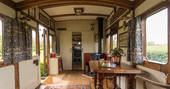beautiful interior of vintage train carriage with mahogany panelling and a Persian rug on the floor at Camping Coach, Dorset