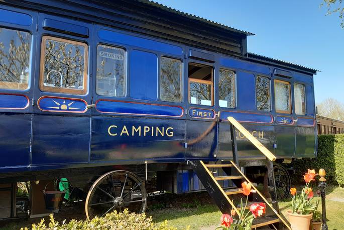 Exterior of quirky train carriage Camping Coach on the grass, Dorset